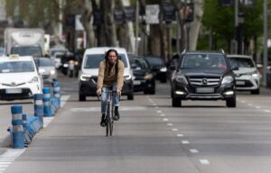 Un ciclista circula por una vía urbana mientras varios coches avanzan detrás de él.