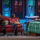 Tres personas conversan en un sofá y una mesa de un plató televisivo.