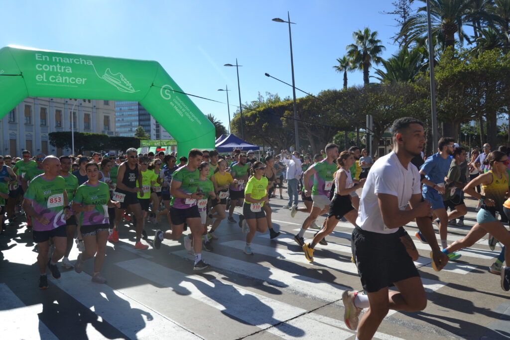 Corredores participan en una carrera bajo el arco verde de lucha contra el cáncer