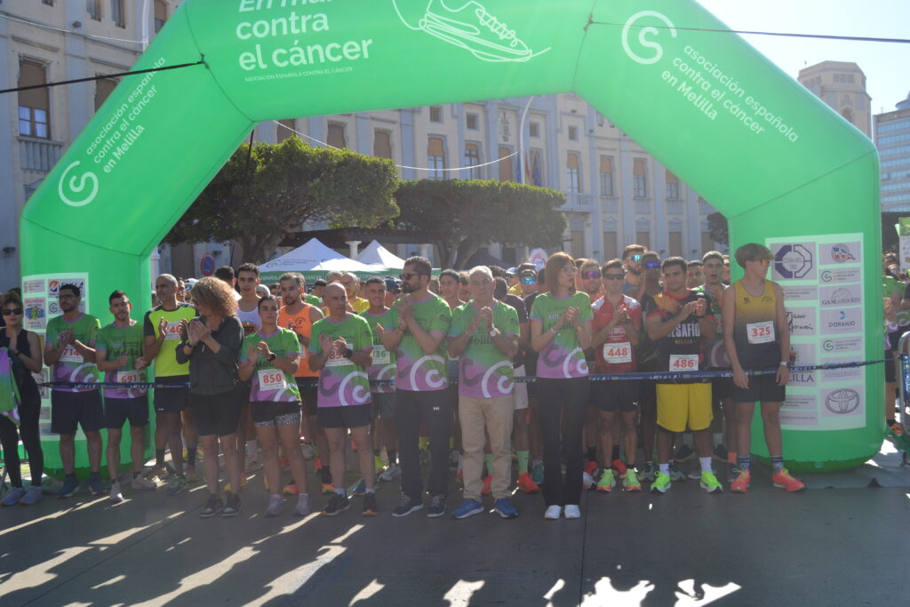 Corredores reunidos bajo un arco verde de la Asociación Española Contra el Cáncer en Melilla