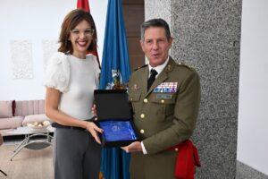 La delegada entrega un reconocimiento al comandante general en un evento oficial.