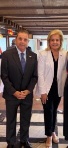 Un hombre y una mujer posan en un salón con una bandera española al fondo.