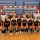 Jugadoras y dos hombres posan frente a una portería de fútbol sala