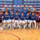 Grupo de jugadores de fútbol sala posa frente a una portería en una cancha cubierta