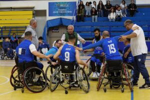 Jugadores de baloncesto en silla de ruedas se reúnen en la pista durante una charla.
