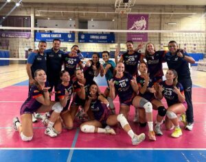 Jugadoras y miembros del equipo posan juntos en una pista de voleibol