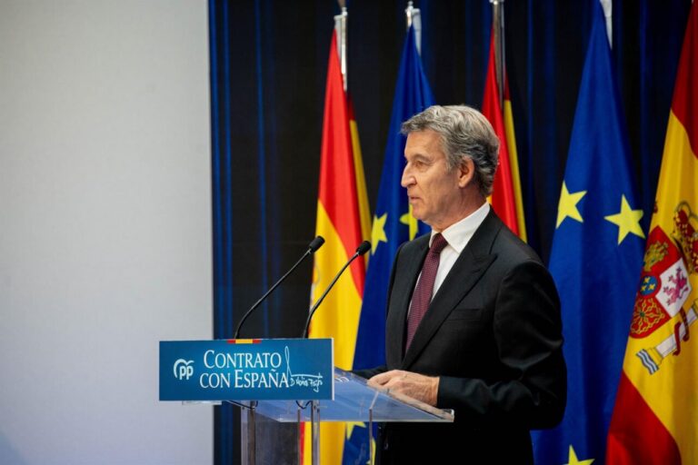 Alberto Núñez Feijóo junto a un atril del PP, con banderas al fondo.