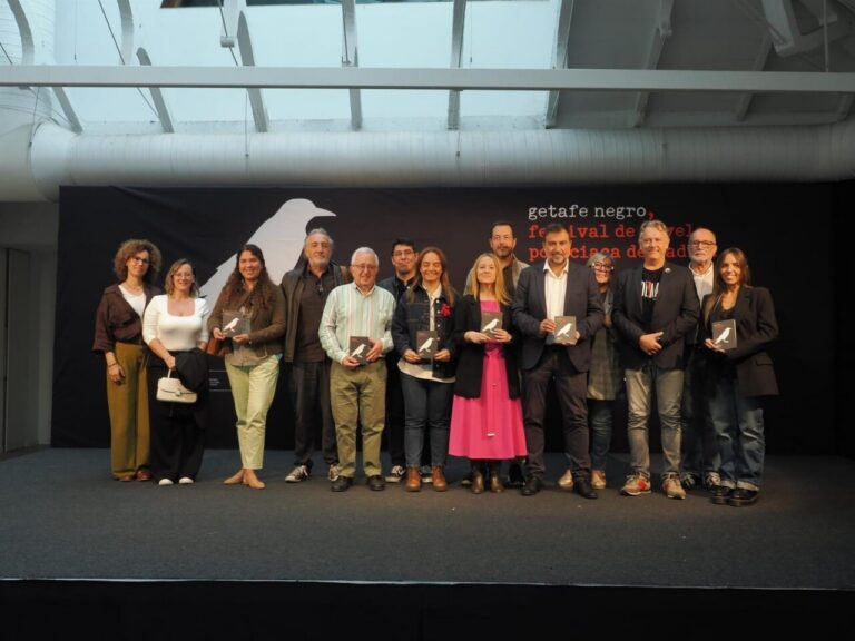 Grupo de personas posa en un escenario ante el fondo del festival Getafe Negro.