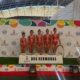 Cinco gimnastas con maillots rojos posan ante un panel de Dos Hermanas.