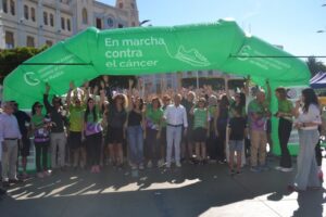 Personas posan bajo un arco verde de la marcha contra el cáncer en Melilla