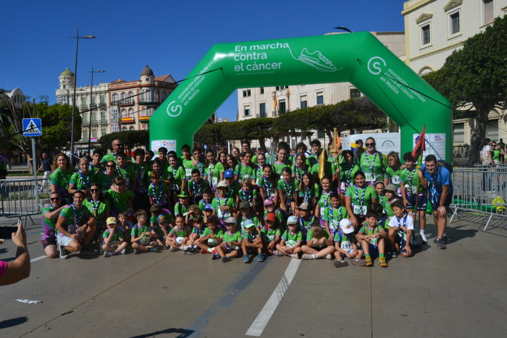 Grupo de participantes posa bajo el arco verde de En marcha contra el cáncer.