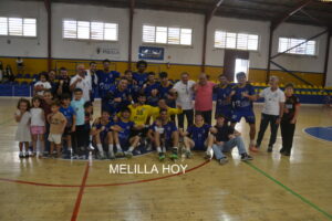 Jugadores de balonmano y niños posan juntos en una pista cubierta.