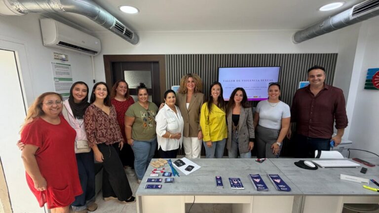 Grupo de personas posa frente a una pantalla en una sala de reunión.