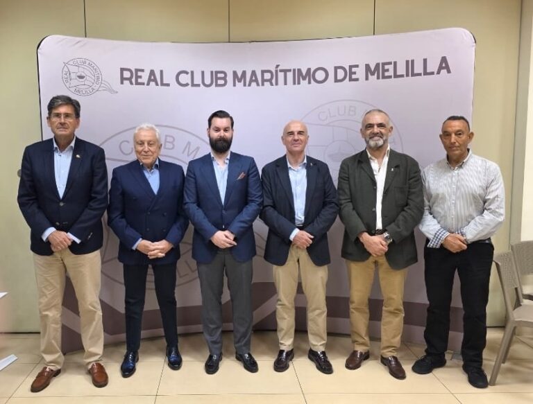 Seis hombres posan frente a un cartel del Real Club Marítimo de Melilla