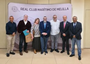 Siete personas posan ante un cartel del Real Club Marítimo de Melilla.