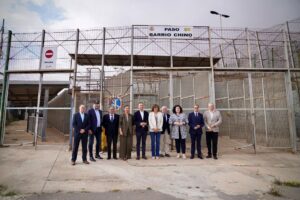 Grupo de diez personas posa frente a una entrada vallada con el rótulo Paso Barrio Chino
