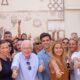 Grupo de personas posa; varias levantan el pulgar y muestran folletos con mensajes políticos.