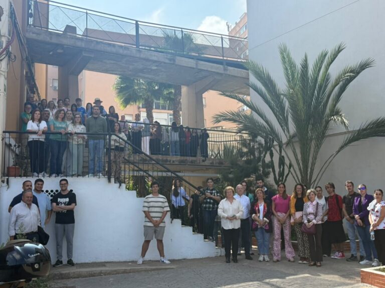 Grupo de personas reunido en un patio junto a una escalera exterior.