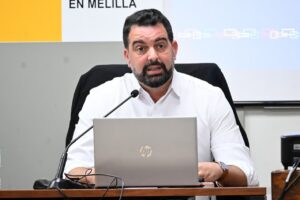 Hombre sentado ante un portátil y un micrófono en una mesa, en Melilla.