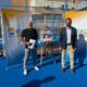 Dos hombres junto al cartel del torneo FIP Gold en una pista de pádel