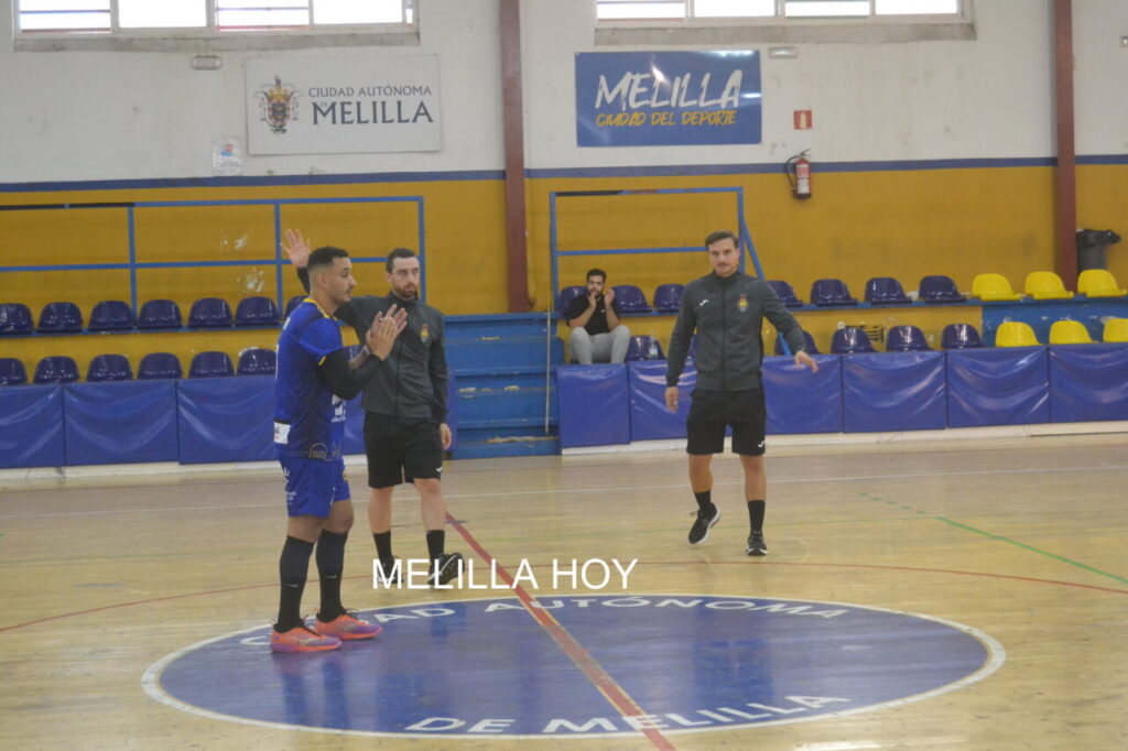Varios hombres en una pista cubierta de balonmano, junto a las gradas.