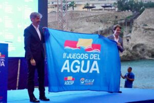 Dos hombres sosteniendo una bandera de los Juegos del Agua en Melilla
