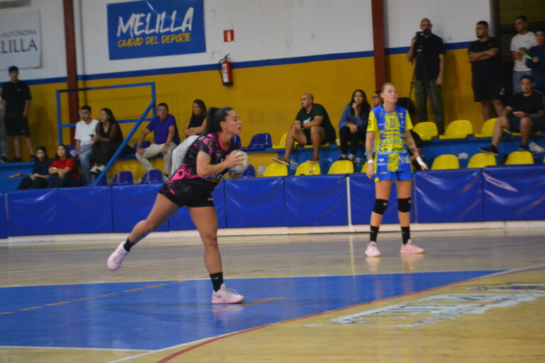Una jugadora de balonmano sostiene el balón durante una acción en una pista cubierta.