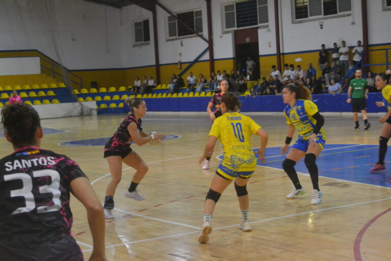 Jugadoras de balonmano con uniformes amarillos y negros disputan una jugada en una pista cubierta