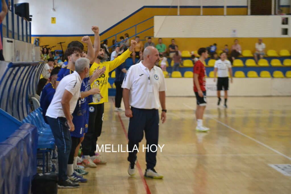 Jugadores de balonmano animan desde la banda mientras el partido continúa en pista