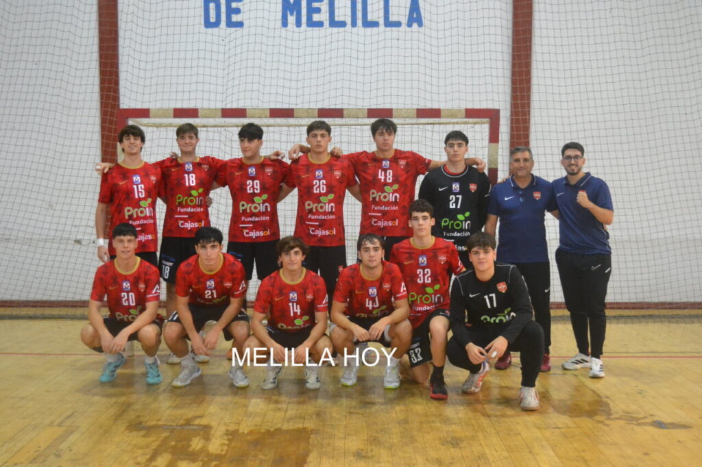 Grupo de jugadores de balonmano con camisetas rojas posa en una pista cubierta.