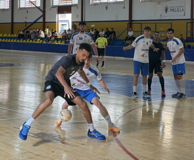 Jugadores disputan un balón durante un partido de balonmano en una cancha cubierta