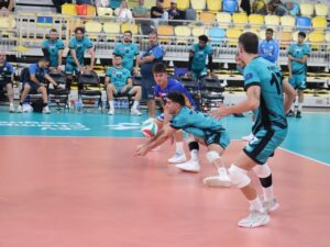 Jugadores de voleibol realizan una recepción de balón durante una sesión en pista cubierta.