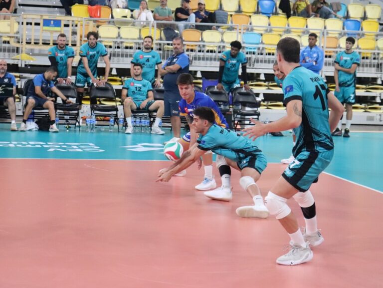 Jugadores de voleibol realizan una recepción de balón durante una sesión en pista cubierta.