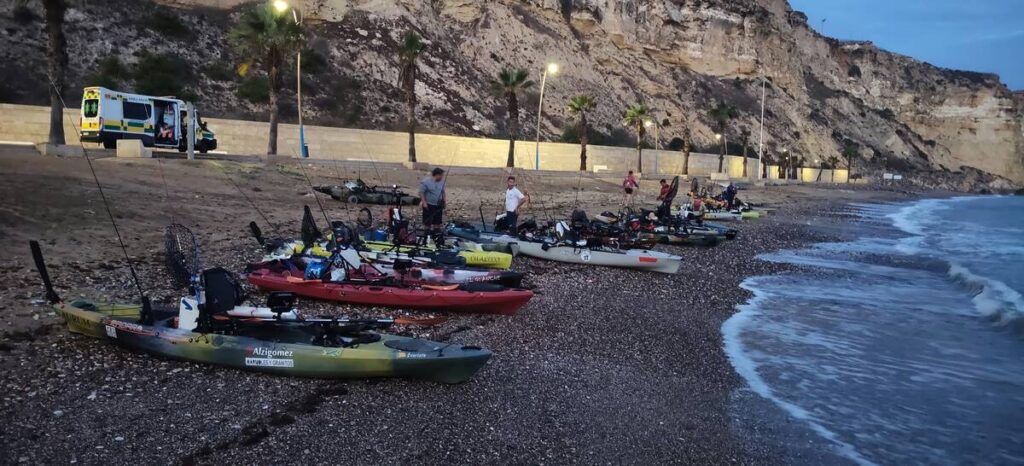Varios kayaks con cañas y equipo de pesca descansan en una playa junto al mar