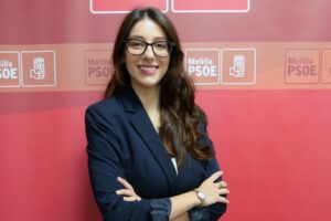 Retrato de Lucía Rubio ante un fondo con logotipos del PSOE de Melilla