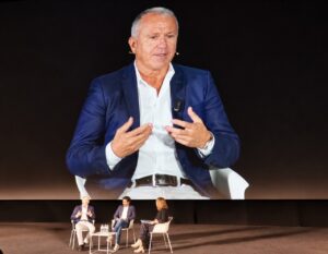 Miguel Marín aparece en una pantalla mientras participa sentado en un panel.