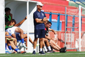 Entrenador Miguel Rivera observando a su equipo en el banquillo durante un partido