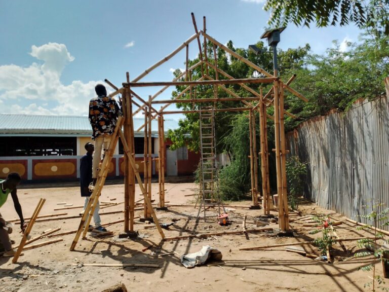 Personas montan una estructura de madera en un patio junto a un edificio.