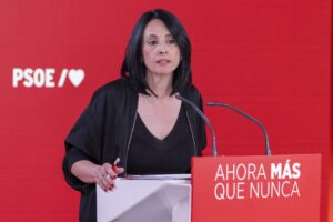 Mujer ante un atril con micrófonos y el logotipo del PSOE al fondo