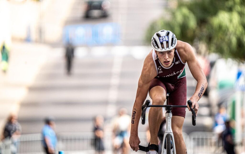 Un triatleta con casco pedalea inclinado sobre su bicicleta durante una competición.