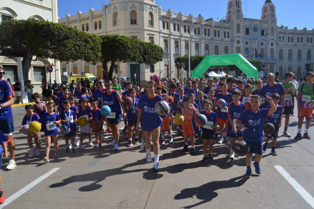 Grupo de jóvenes y adultos con balones frente al arco de la marcha contra el cáncer