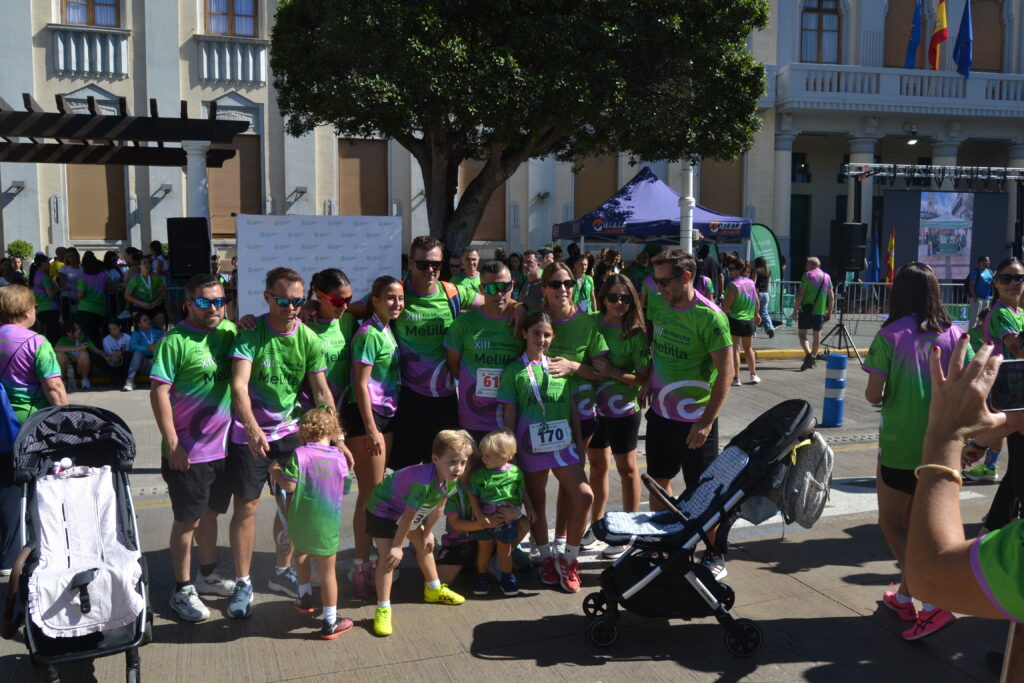 Grupo de participantes con camisetas verdes y moradas posa junto a varios niños en una plaza