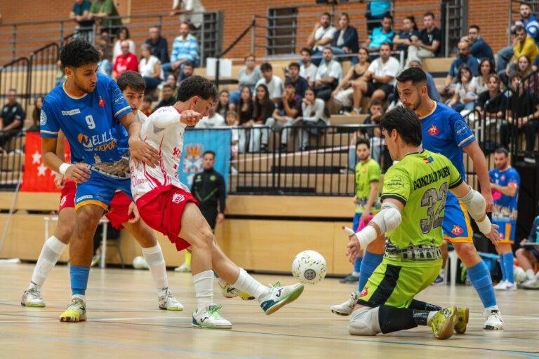 Jugadores disputan el balón durante un partido de fútbol sala en una pista cubierta.