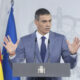 Pedro Sánchez habla ante un atril con micrófonos y banderas institucionales.