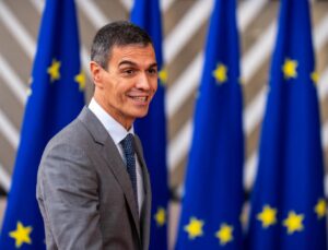 Pedro Sánchez, con traje gris, frente a varias banderas de la Unión Europea