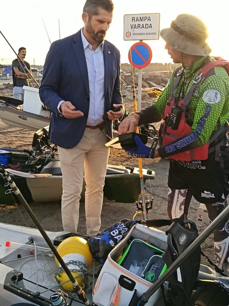 Dos personas junto a kayaks y equipo de pesca en una rampa costera