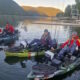 Tres personas en kayaks de pesca, con cañas y redes, sobre agua tranquila