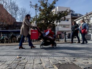 Mujer empujando un carrito de bebé en la calle con otras personas