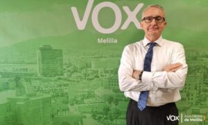 Hombre con camisa blanca y corbata posa ante un fondo verde de Vox Melilla.