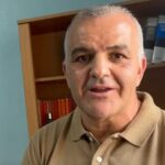 Retrato de un hombre con polo beige frente a una estantería de libros